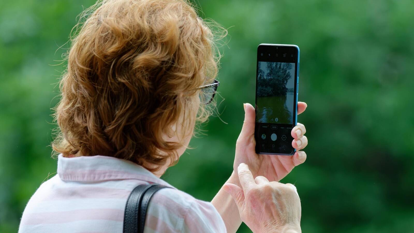 Personne qui photographie au téléphone une poêle en pleine cuisson sur le plan de travail
