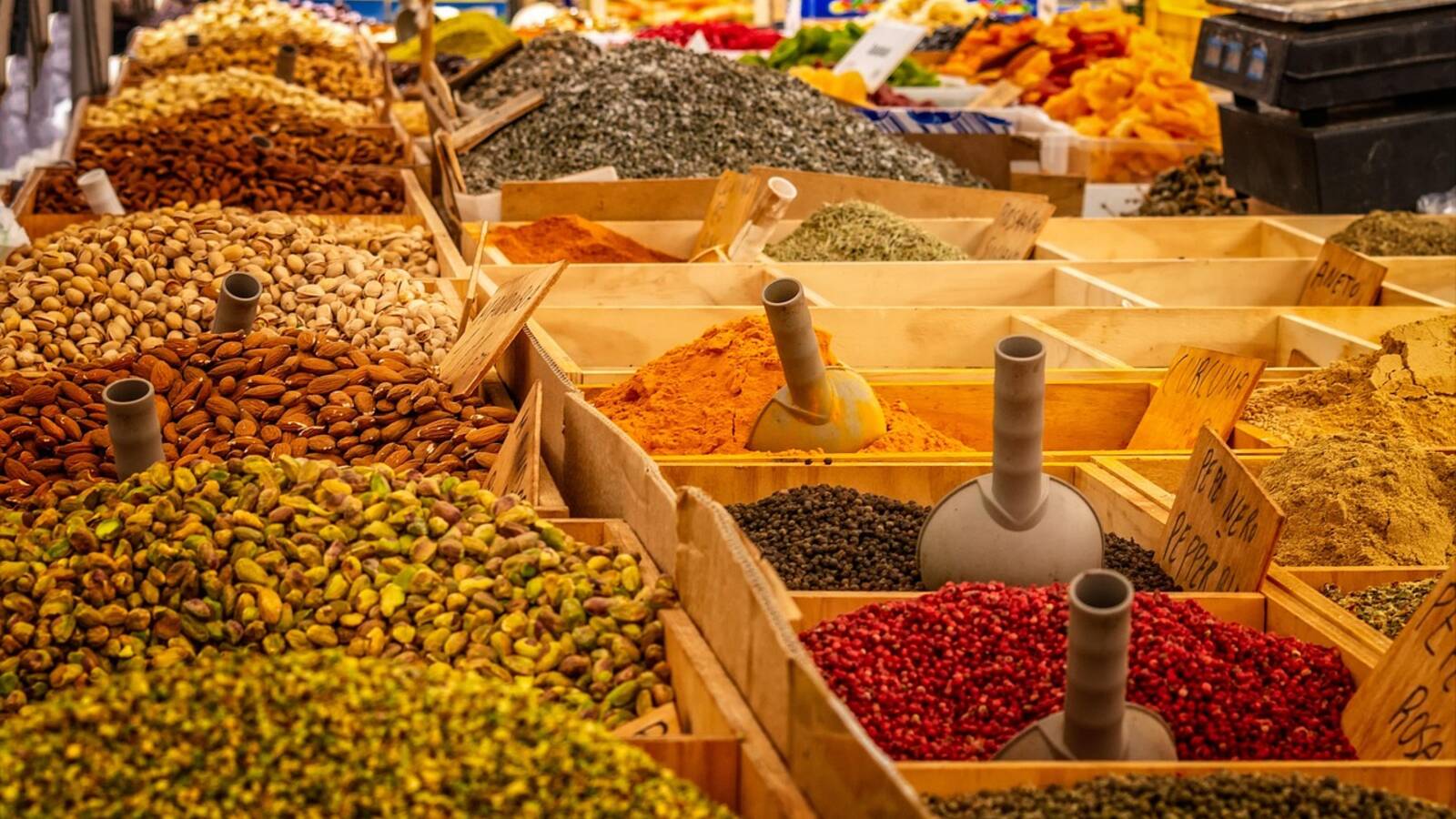 Bols d'épices colorées alignés sur un étal : curcuma, paprika, cumin et piments séchés