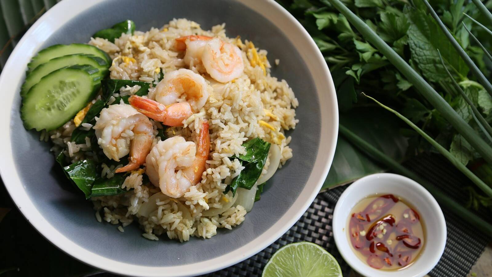 Bol de riz garni de légumes sautés en rangées colorées, d'un œuf au plat et d'une cuillerée de sauce pimentée